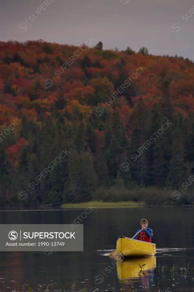 Woman paddling a canoe on Rock Lake in Algonquin Provincial Park, Ontario, Canada.