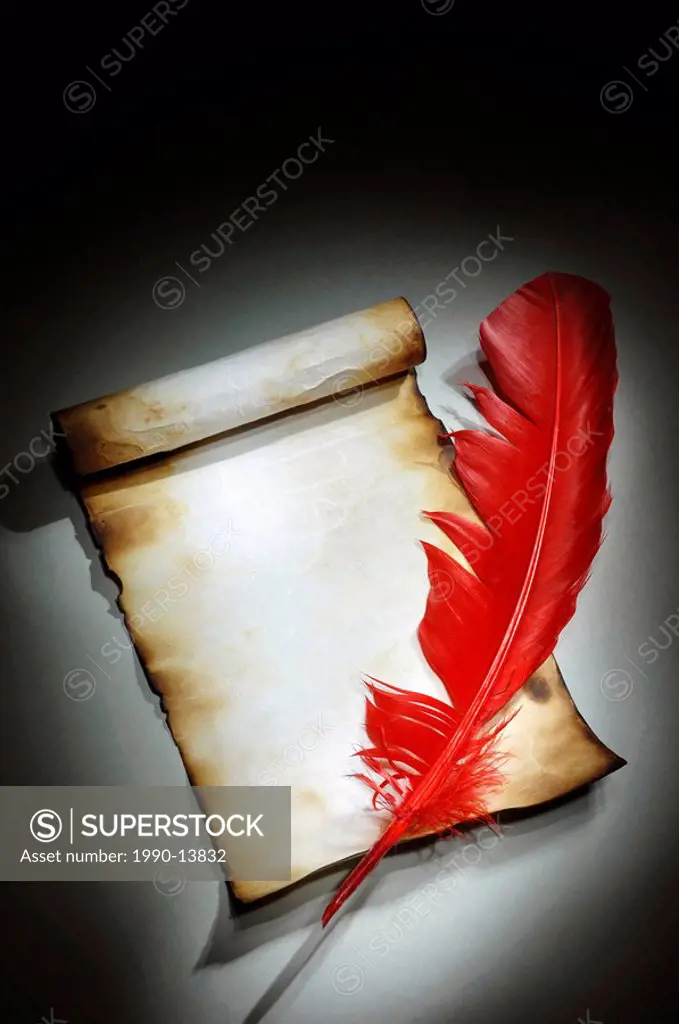 Vintage parchment with burnt edges and a red quill Conceptual artistic light_painted still life on black background