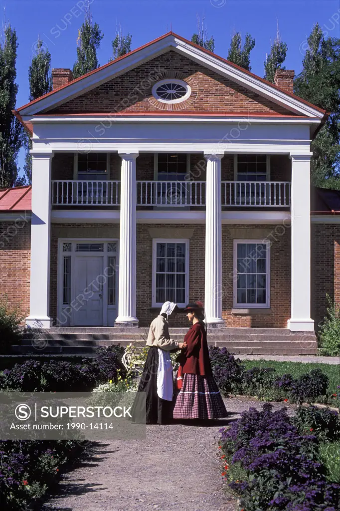 Two pioneer women talking at entrance to Crysler Hall, Upper Canada Village, Morrisburg, Ontario, Canada. Upper Canada Village is a heritage park on t...
