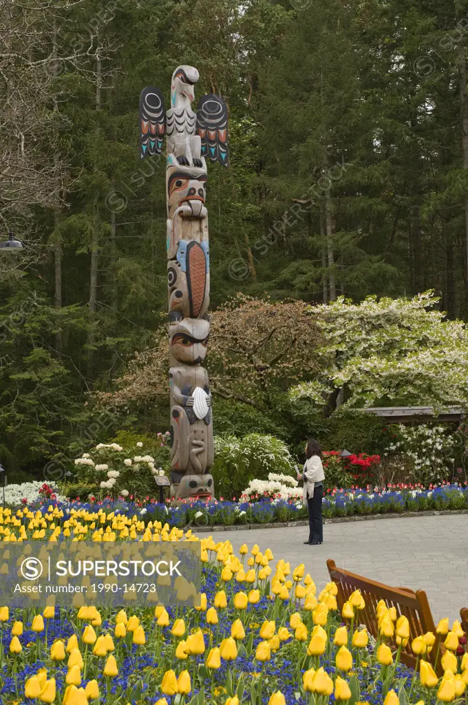 Tourist viewing totem pole, Butchart Gardens, Victoria, Vancouver Island, British Columbia, Canada