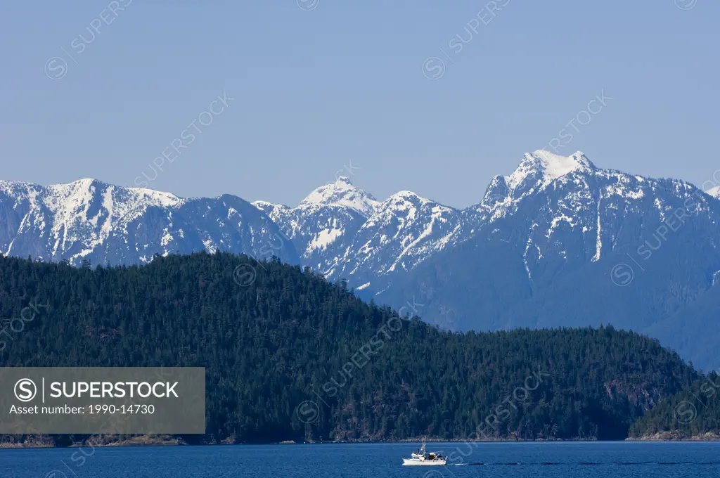 View eastward from Cortes Island to Coast Range mountains with small fishing boat in the distance, British Columbia, Canada