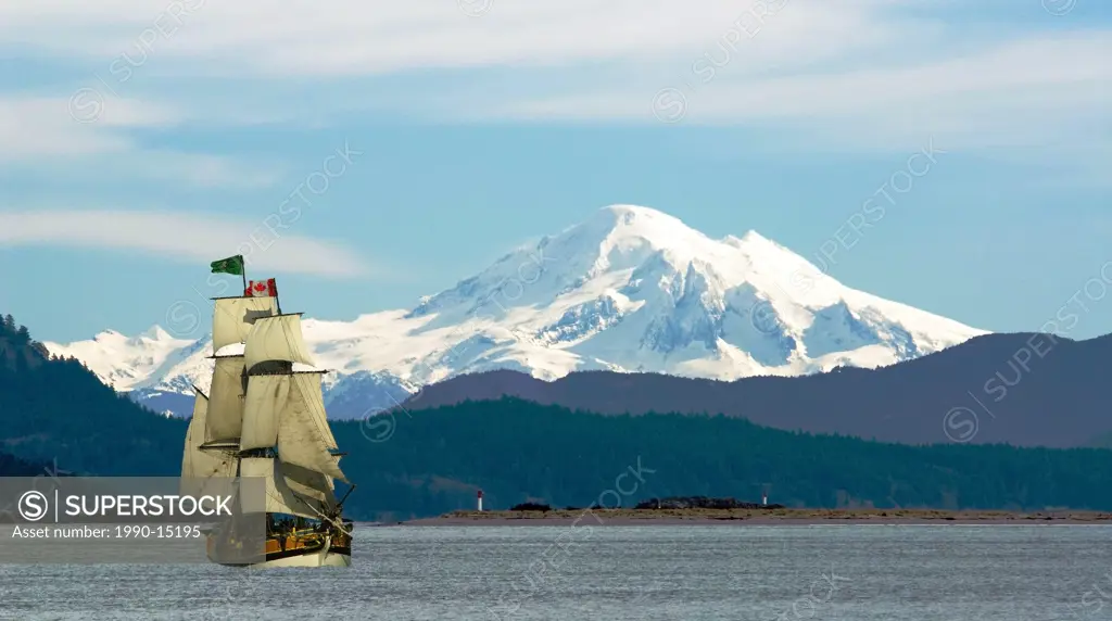 Mount Baker and Sidney Island are a backdrop to the tall ship Lady Washington sailing off Saanich Peninsula on Vancouver Island, British Columbia, Can...