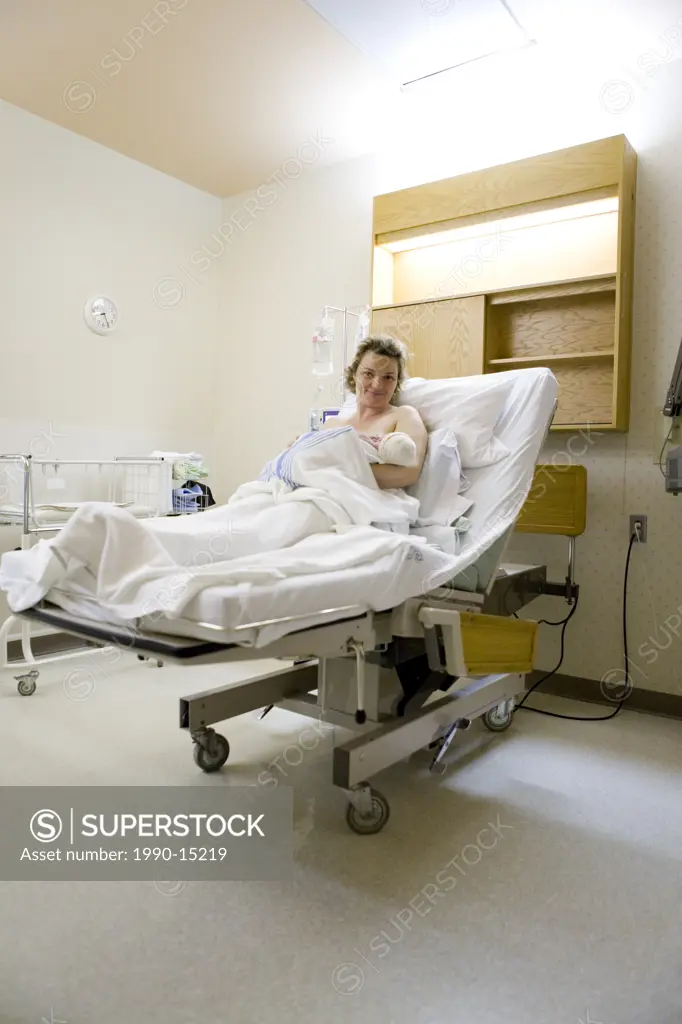 36 year old woman lying in hospital bed with newborn in her arms, Chateauguay, Quebec, Canada