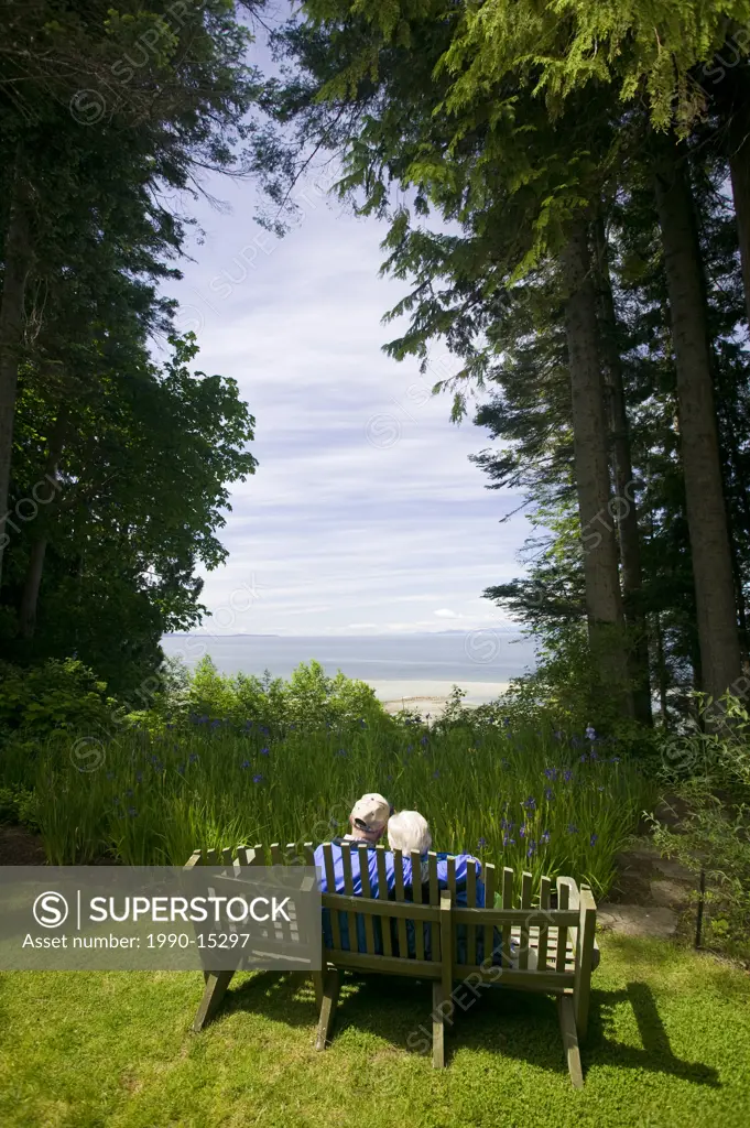 A senior couple sitting on a bench on the grounds at Milner Gardens & Woodland, a seaside garden set in natural coastal Douglas fir woods in Qualicum ...