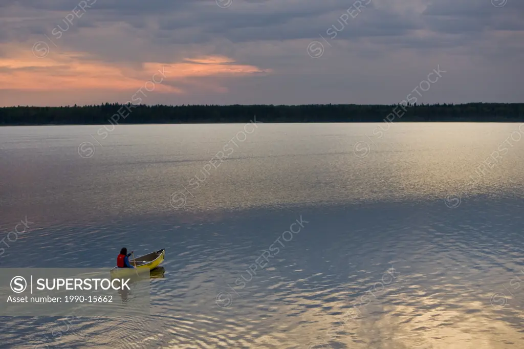 Canoeing on Lake Audy at sunset in Riding Mountain National Park, Manitoba, Canada