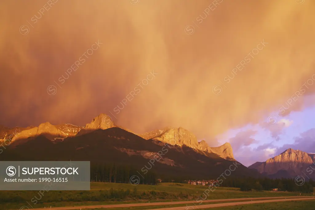 A spectacular sunrise lights up a giant storm cloud over Ha Ling Peak, the Bow Valley and the Trans_Canada Highway in Canmore, Alberta, Canada