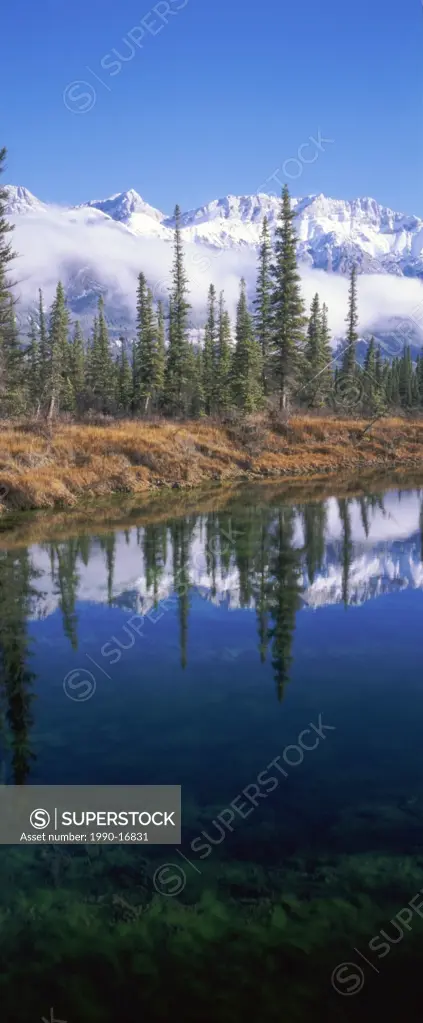 Early snow on Miette Range and reflection in a pond along Highway 16 close to Rocky River, Rocky Mountains, Jasper National Park, Alberta, Canada