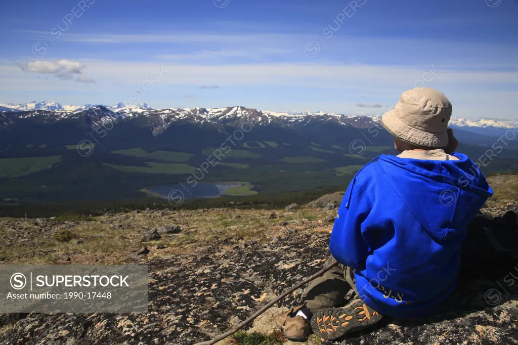 Young hiker taking break in alpine overlooking valley, Smithers, British Columbia