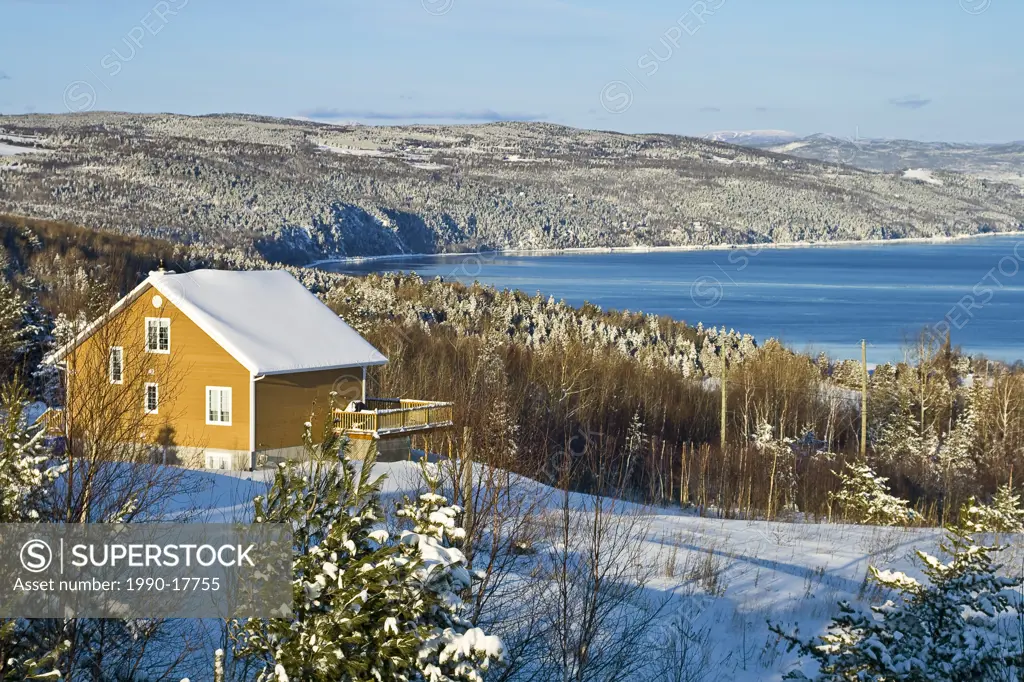 Snow covered home and trees overlooking the St. Lawrence River after a snowstorm. View towards La Malbaie, Charlevoix, Quebec, Canada