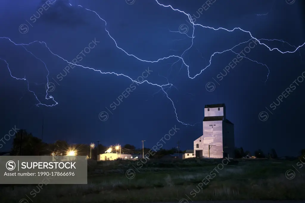 Storm with lightning over old grainery in rural Elkhorn, Manitoba, Canada
