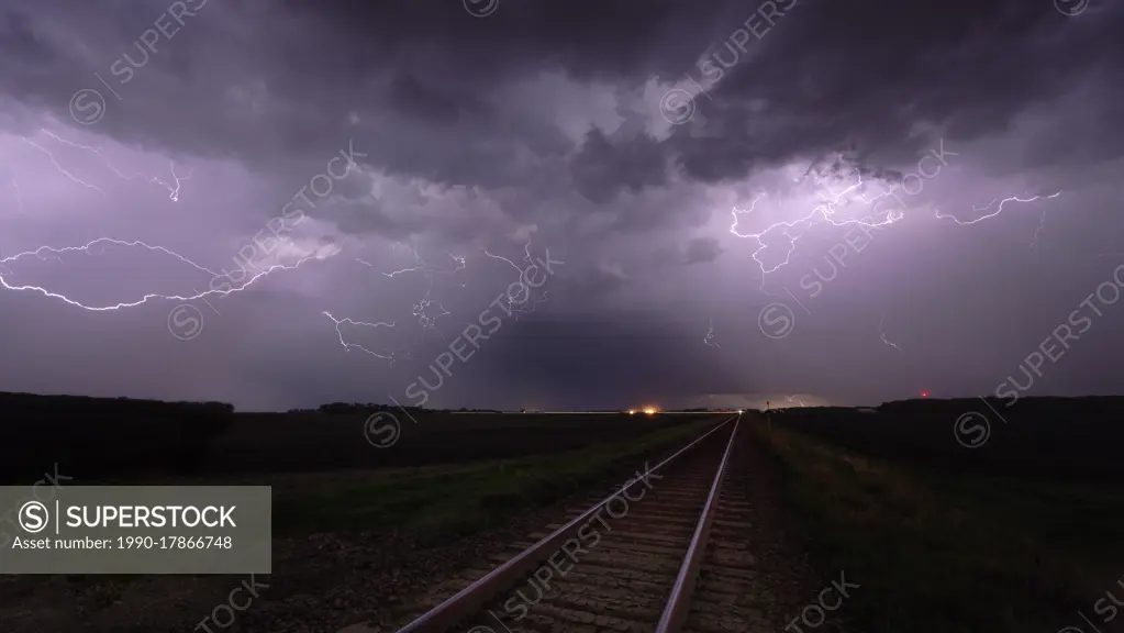 Storm with lightning flashing overhead railway crossing and train tracks in southern Manitoba, Canada