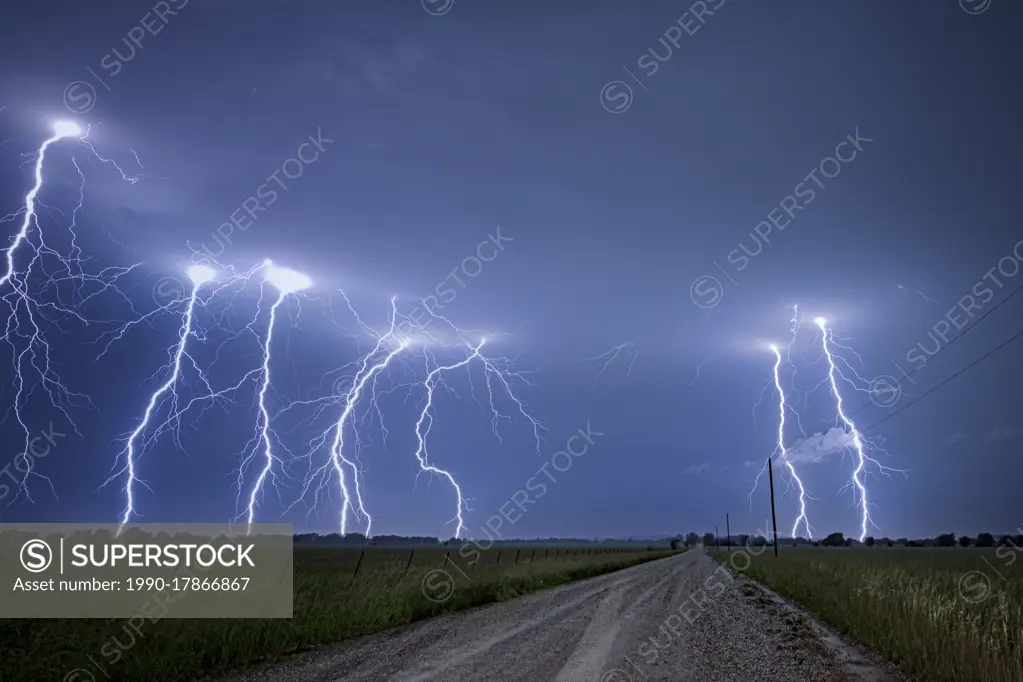 Storm with cloud to ground lightning flashing over old rural road in Kansas United States 4 image composition