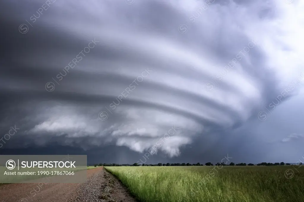 Mesocyclone building and spinning over a field and gravel road in Kansas United States