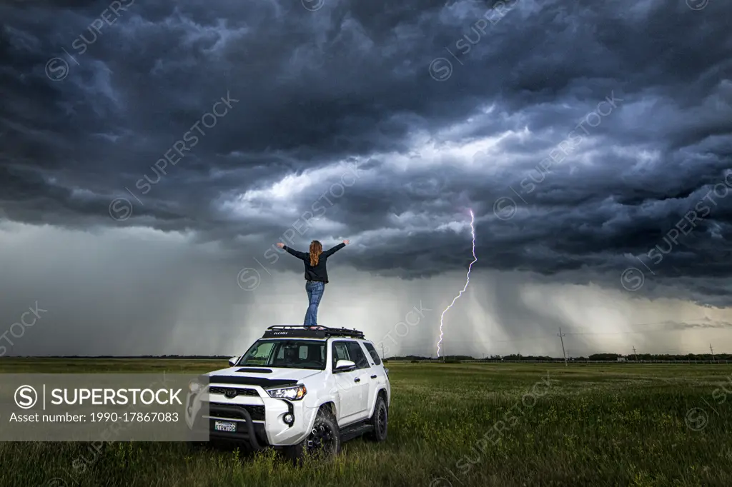 Self portrait on top of my truck with storm and lightning in the distance in rural Manitoba Canada