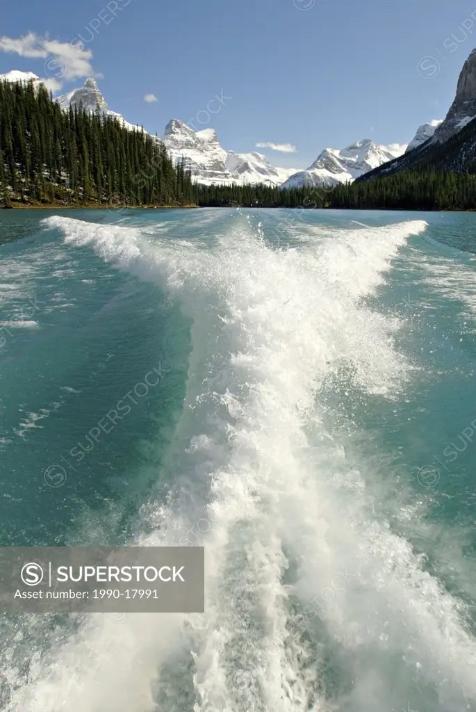 Looking back at the flowing aquawa colored water and the snow capped magnifficent Rocky mountains from a tour boat on the Maligne Lake in Jasper Natio...