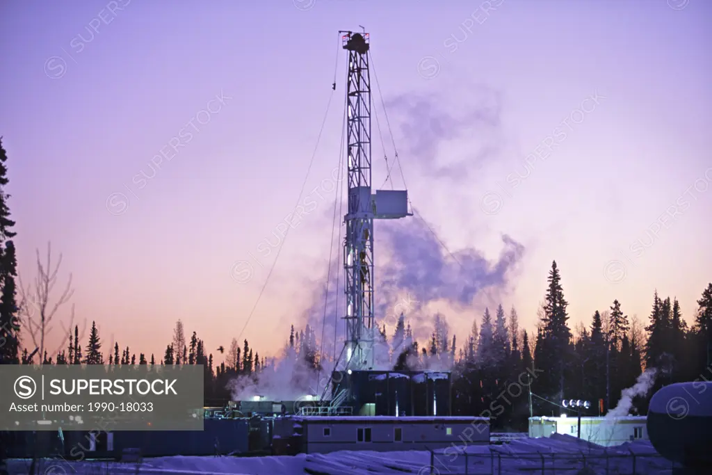 An image of a working drill rig with an early morning sunrise background in western Alberta, Canada exploring for gas and oil.