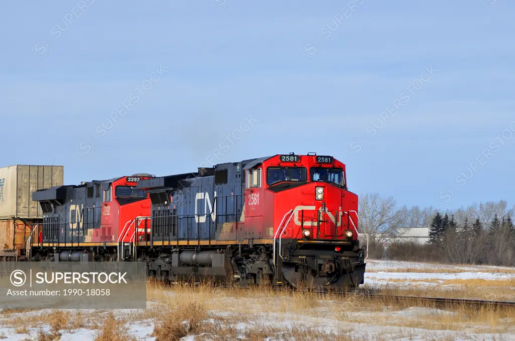 A close up image of two train engines pulling rail cars loaded with containers.