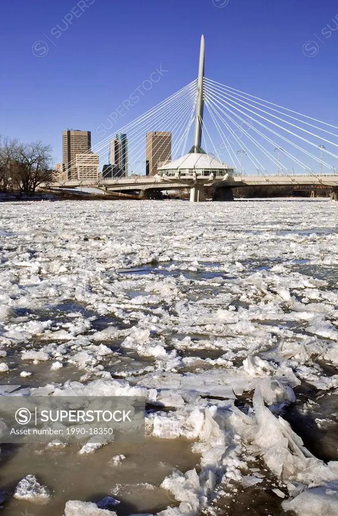 Ice forming on the Red River, Esplanade Riel Bridge and Winnipeg skyline in the background. Winnipeg, Manitoba, Canada.