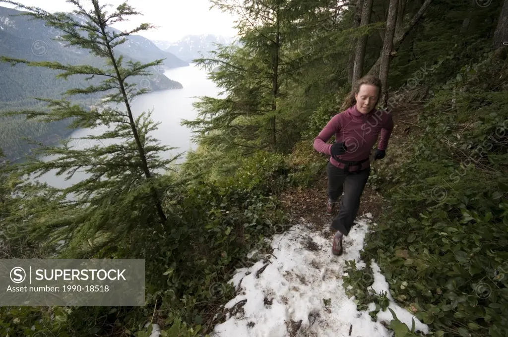 Young woman running on the Diez Vistas Trail. Buntzen Lake Regional Park. Port Moody, British Columbia, Canada