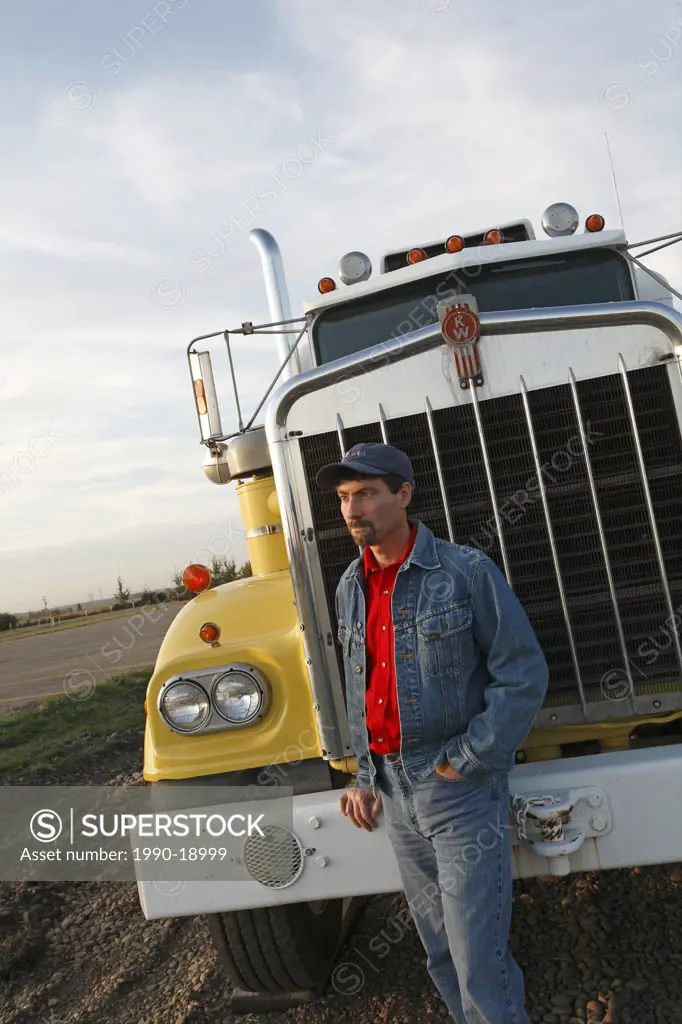 Truck driver standing next to long haul truck, Alberta, Canada