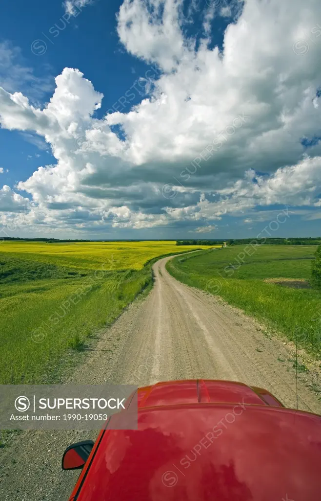 Car driving through farmland on a country road. Tiger Hills, Manitoba, Canada