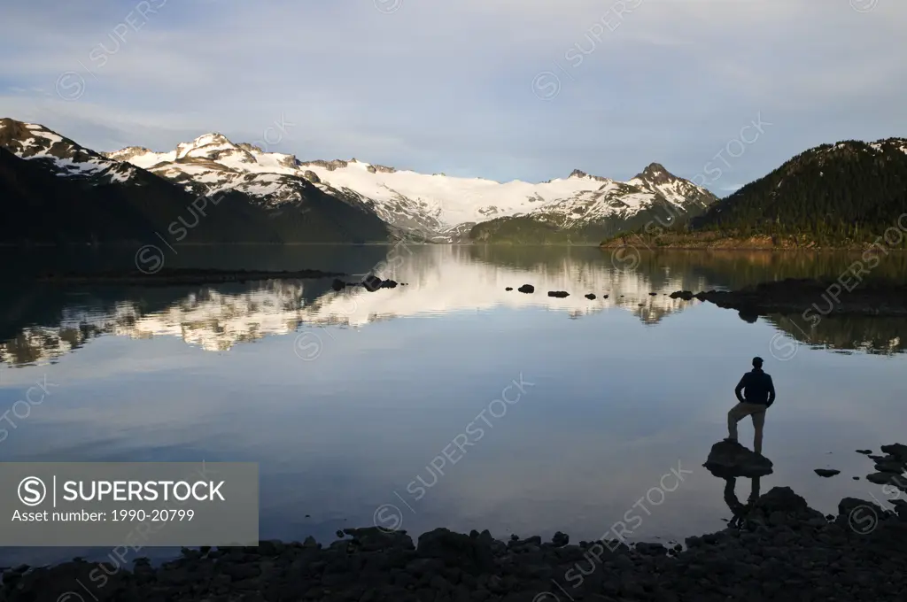 A hiker is silhouetted by the Sphinx Glacier and Garibaldi Lake in Garibaldi Provincial Park near Whistler BC.