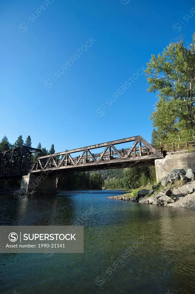 Boy jumping from trestle bridge at Kettle River Provincial Park, BC, Canada