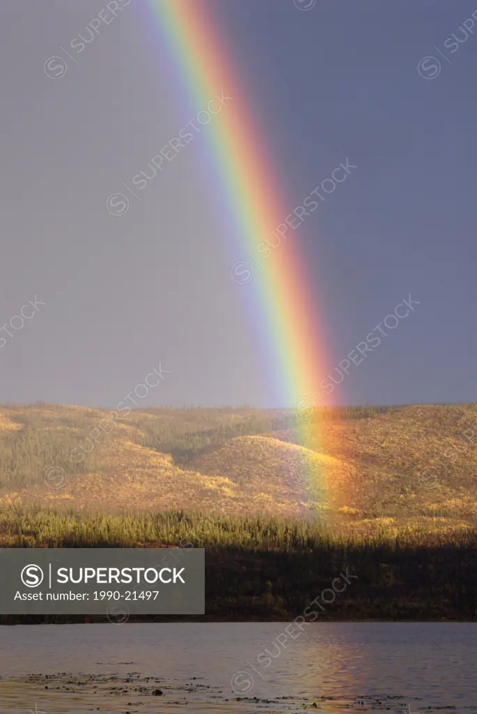 Rainbow on distant shoreline of alpine lake. Un_named lake. Yukon Territory, Canada.