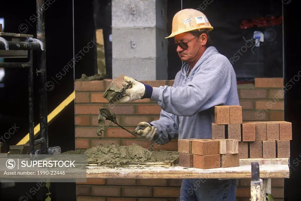 Construction worker  Bricklayer applies mortar while constructing brick wall, British Columbia, Canada