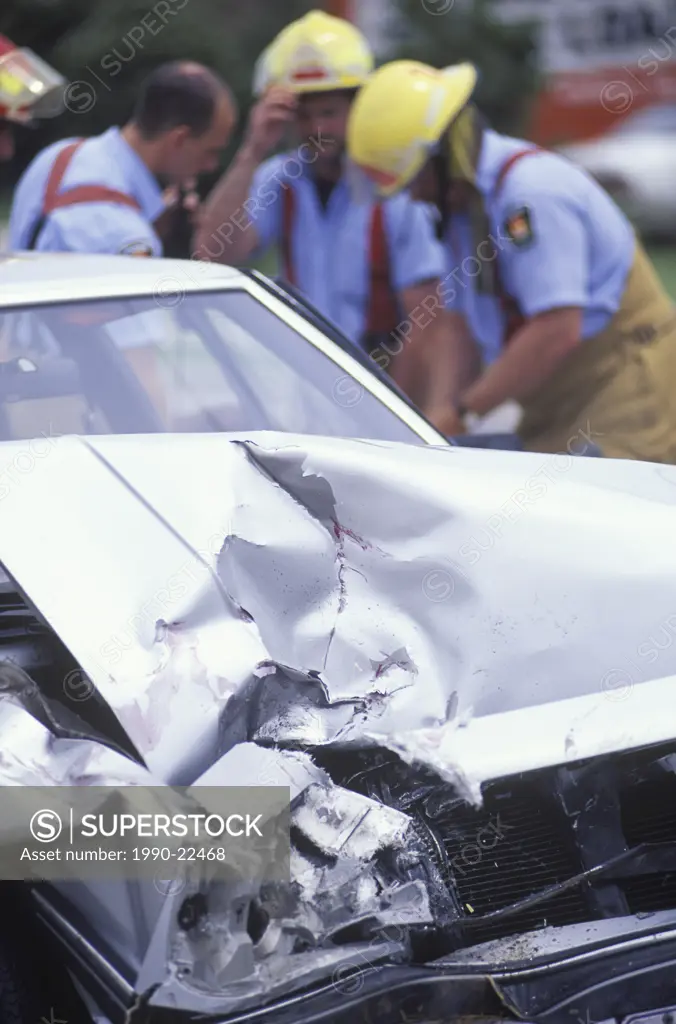 Auto accident - Crumpled car and out of focus emergency workers beyond, British Columbia, Canada