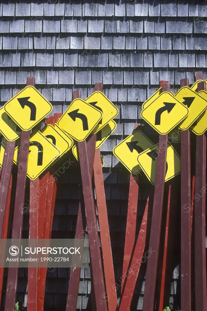 Curve ahead roadsigns bunched together against cedar shingled wall, British Columbia, Canada
