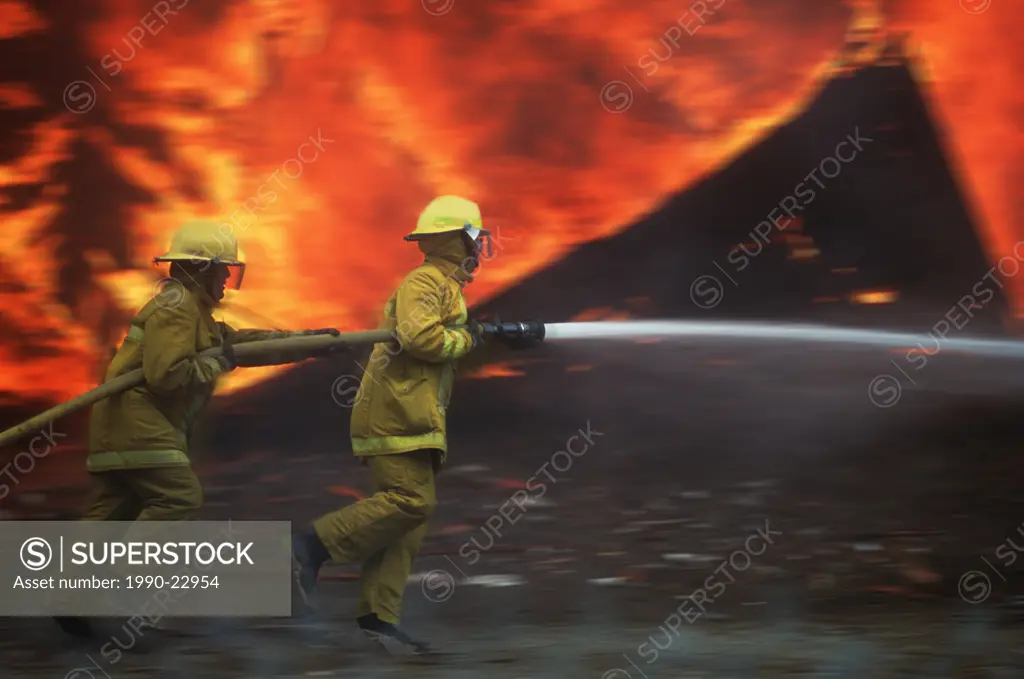 Firefighters with hose move through fire scene to spray flames, Motion blur, British Columbia, Canada