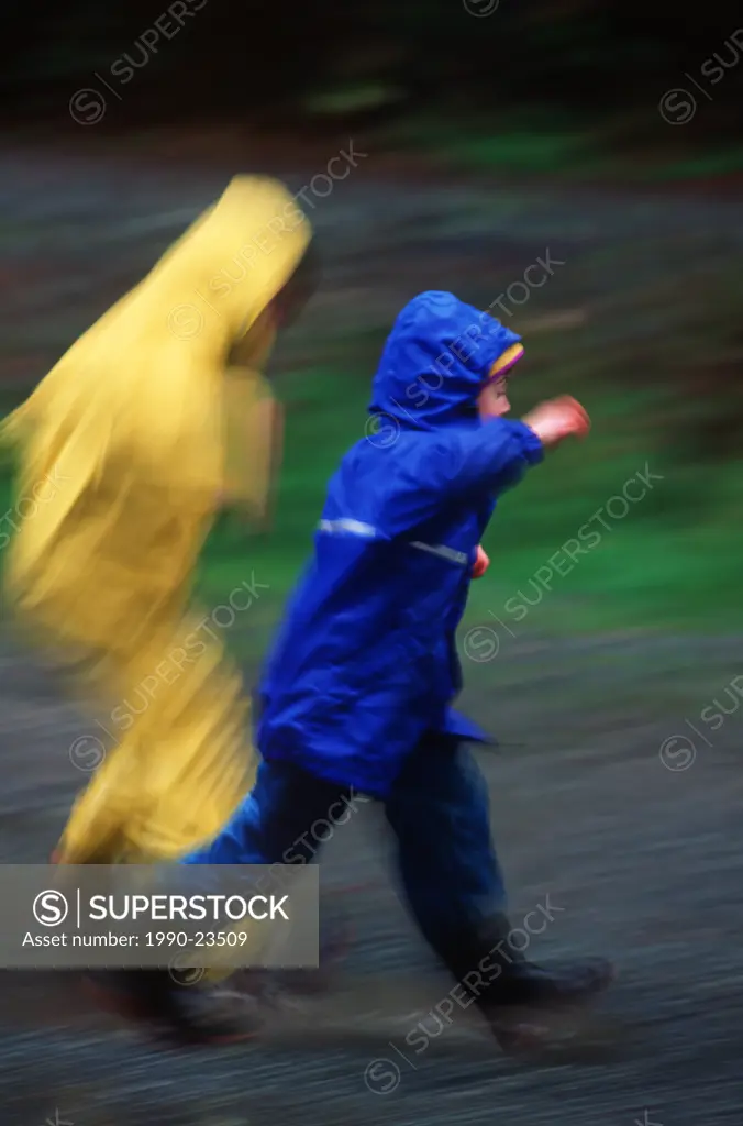2 Boys in raincoats in motion blur, British Columbia, Canada