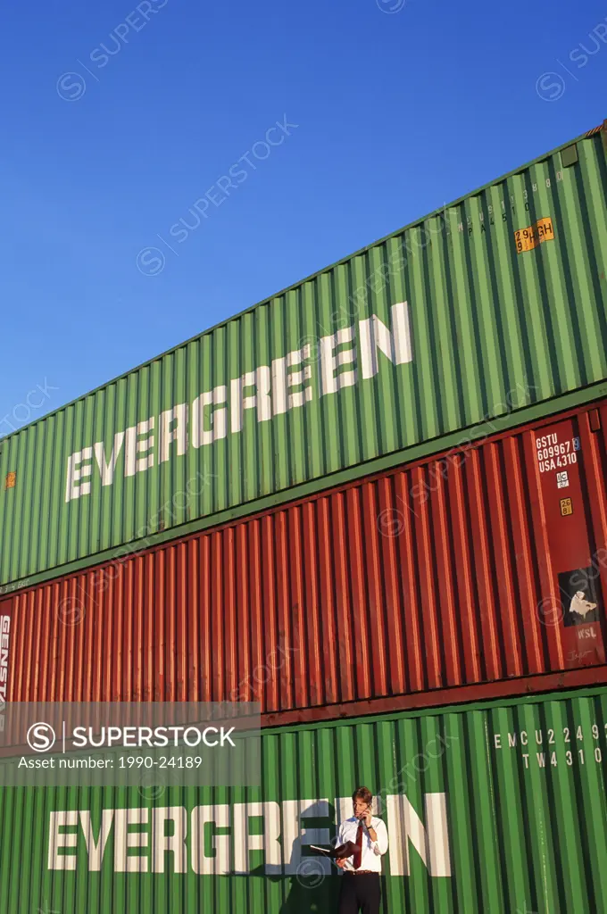 Vancouver port worker checks documents in container storage area, British Columbia, Canada