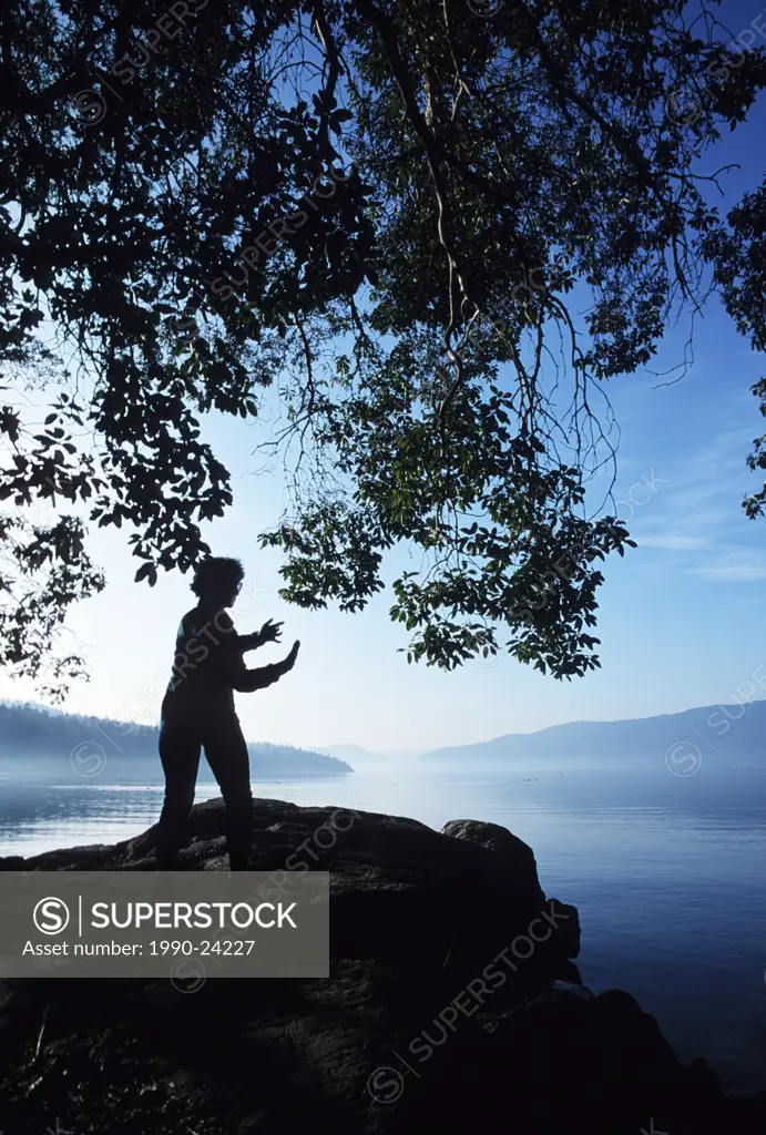 Single woman praticing Tai Chi on the shore, Vancouver Island, British Columbia, Canada