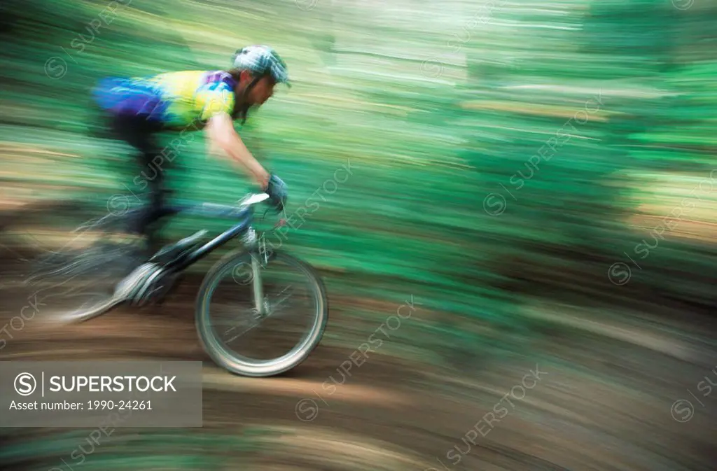 Mountain bike rider on forest trail with pan blur, British Columbia, Canada