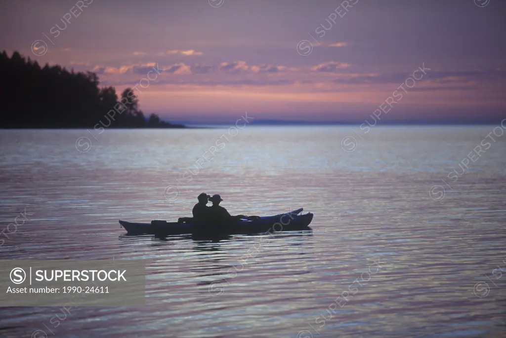 Madrona Point, sea kayakers at dusk, Craig Bay, Parksville area, Vancouver Island, British Columbia, Canada