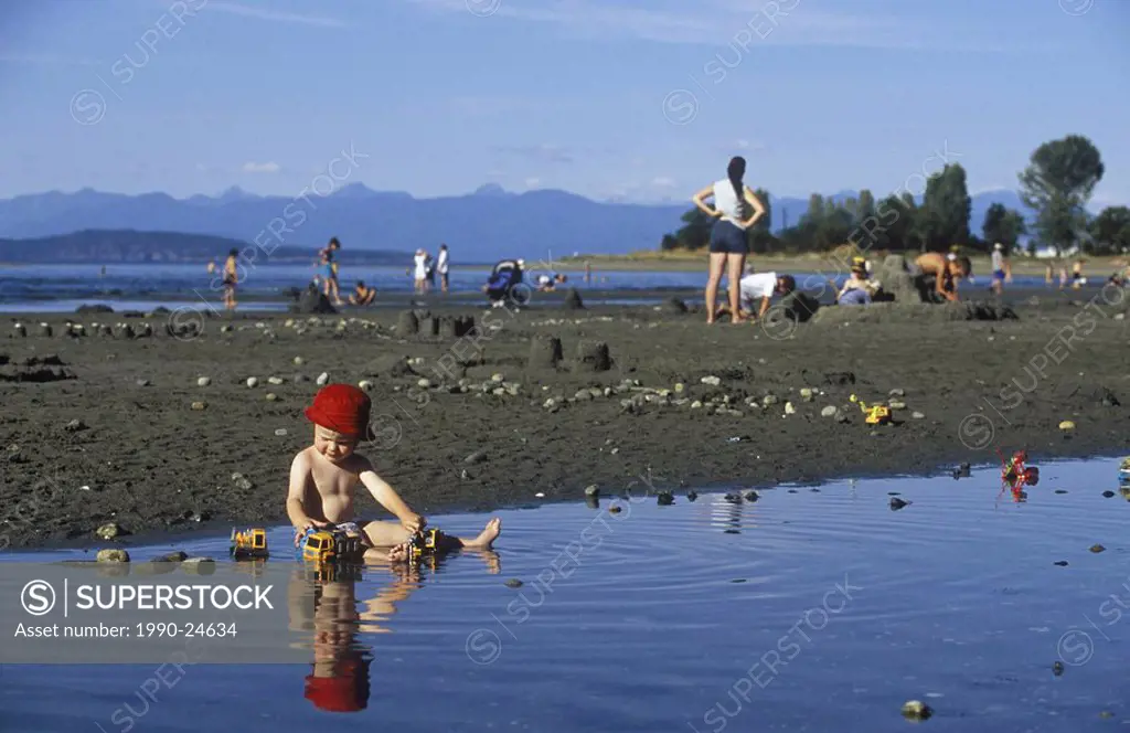Parksville Beach Young boy plays in warm tide pool on beach, Vancouver Island, British Columbia, Canada