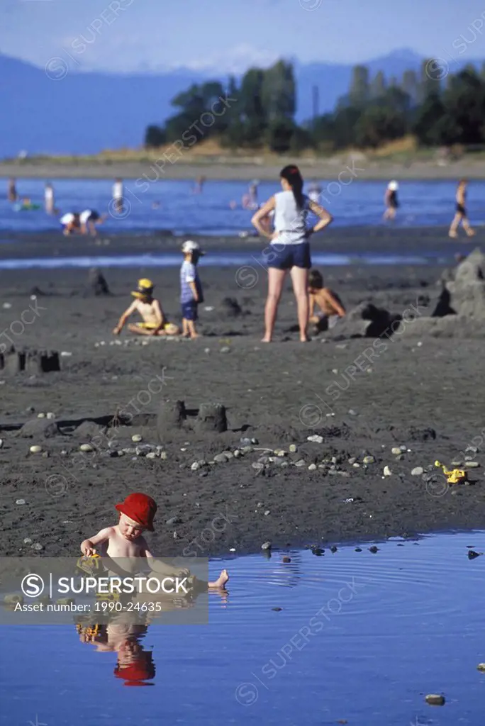 Parksville Beach Young boy plays in warm tide pool on beach, Vancouver Island, British Columbia, Canada