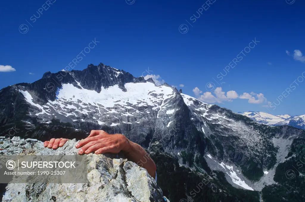 climber hands atop rock peak in Tantalus Range, Whistler, British Columbia, Canada