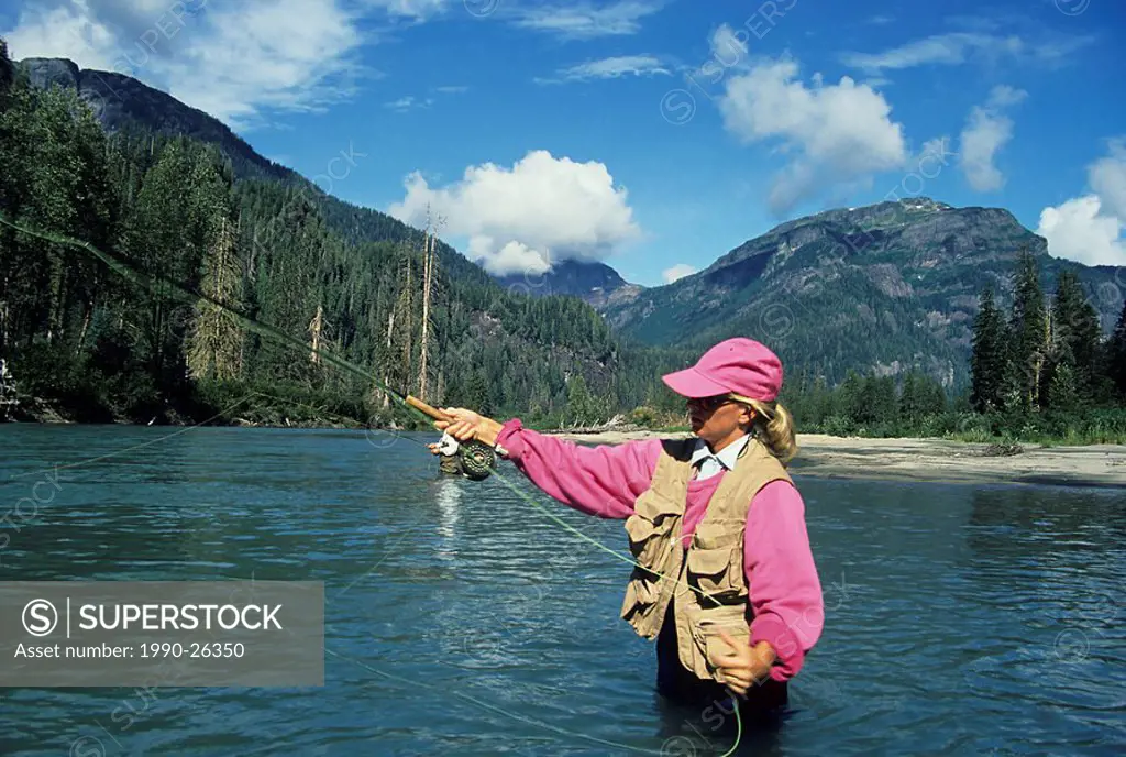 Lady flycaster fishing for salmon, Giltoyees river, Douglas Channel, British Columbia, Canada