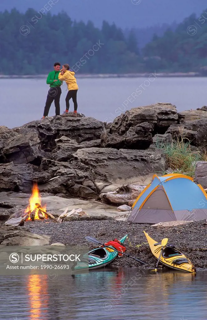 Couple camped on islet while sea kayaking, Hornby Island, British Columbia, Canada