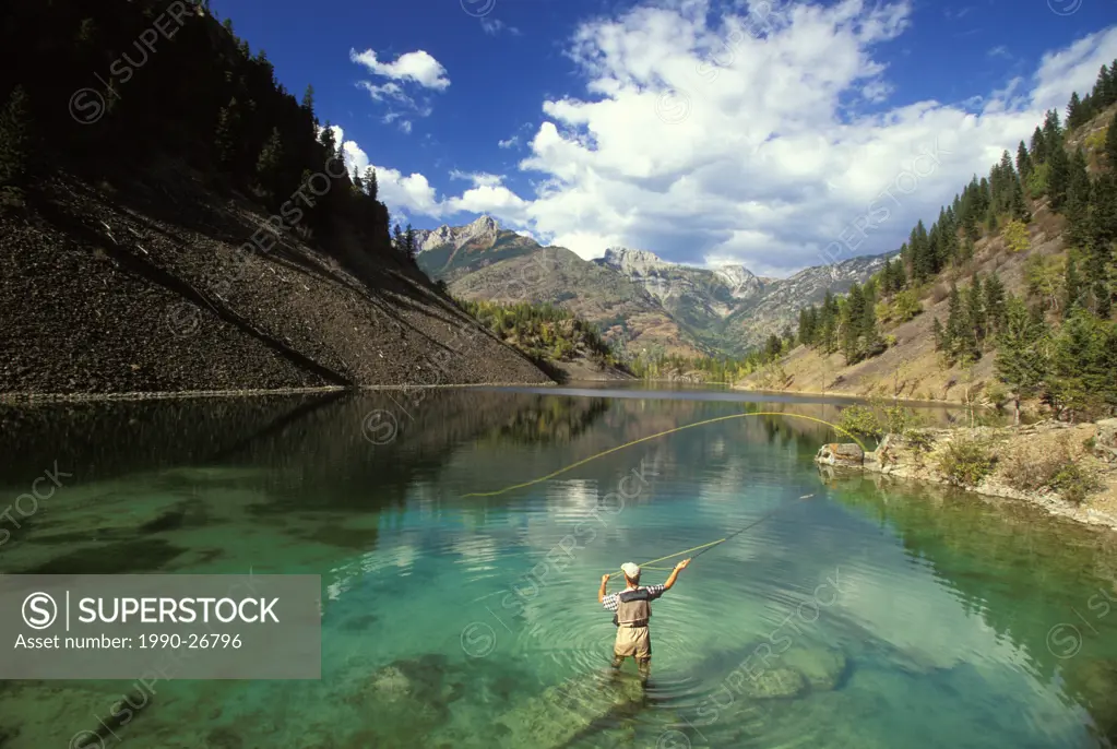Young man fly-fishing on Lower Silver Springs Lake in the Elk Valley near Fernie, British Columbia, Canada