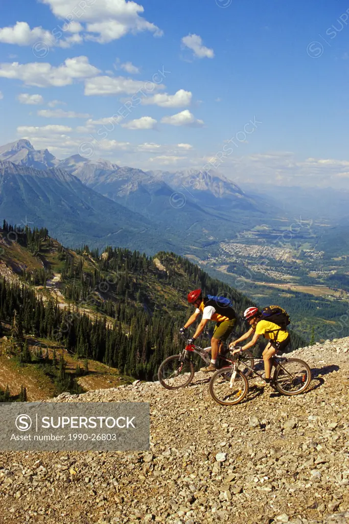 Young couple mountain biking at Fernie Alpine Resort near Fernie, British Columbia, Canada
