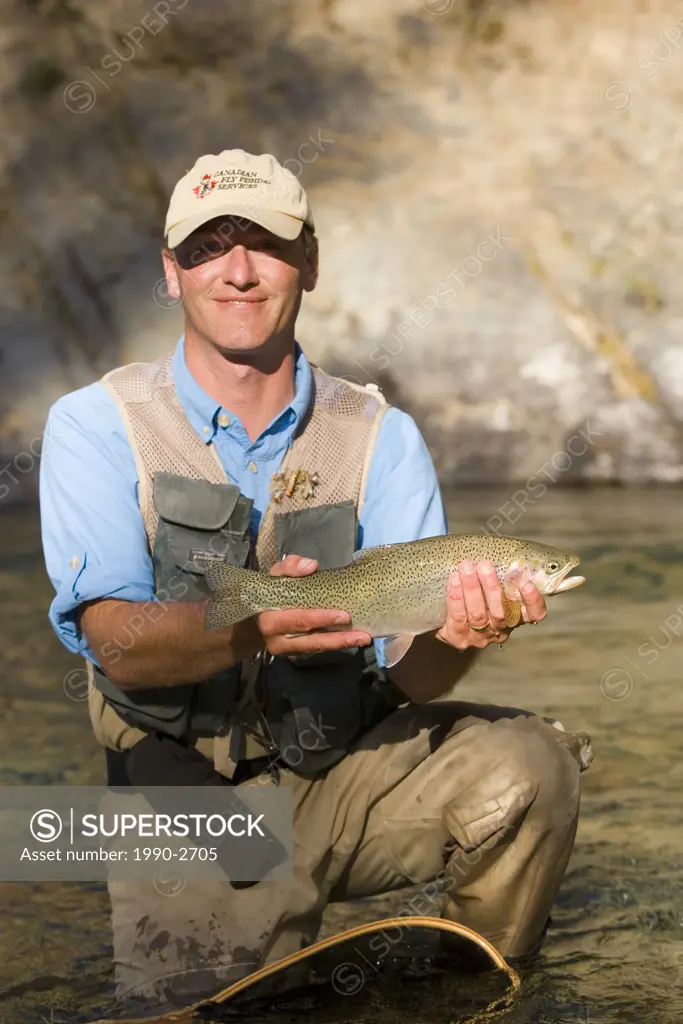 Fly-fishing guide, releases cutthroat trout on tributary of Elk River near Fernie, British Columbia, Canada