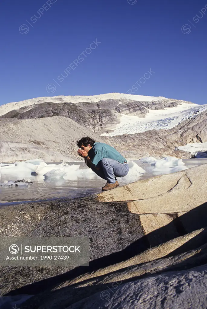 Hiker gets a drink of pure glacier water, British Columbia, Canada