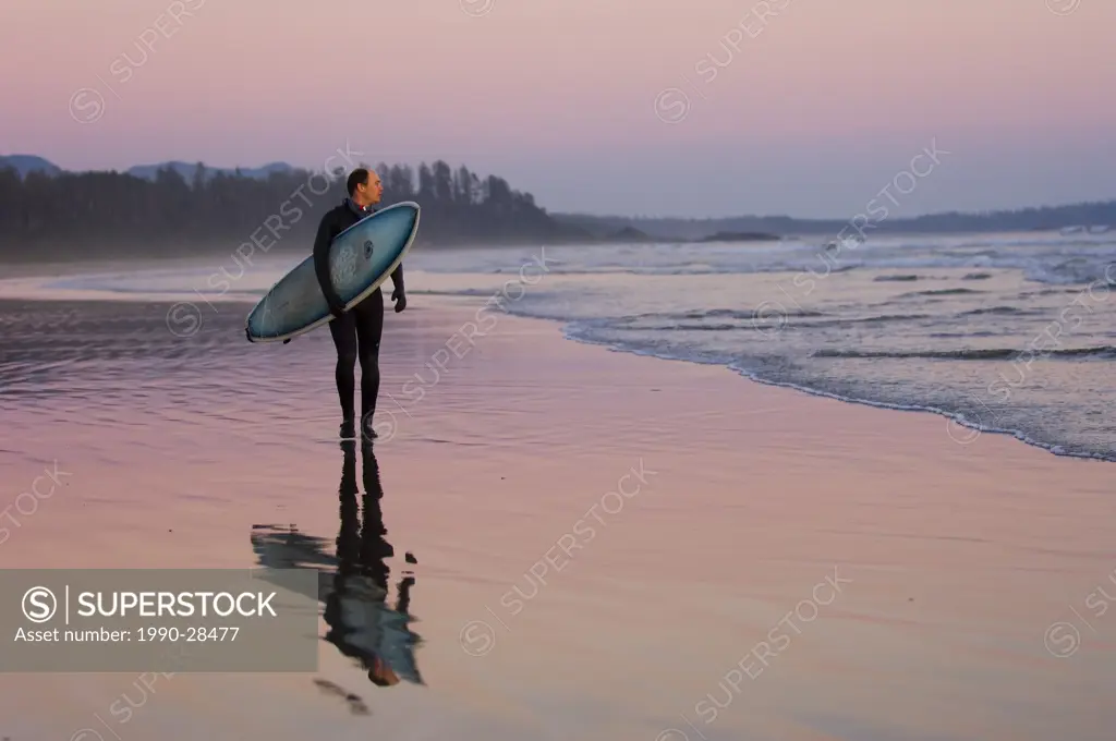 surfer walks shoreline, Pacific Rim National Park, Long Beach, Vancouver Island, British Columbia, Canada