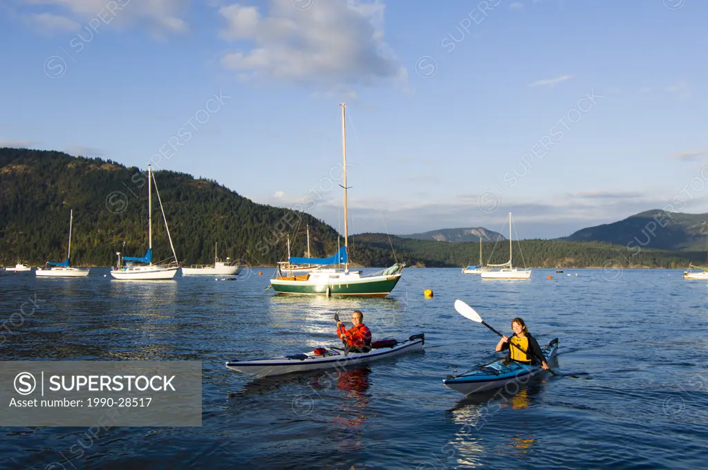 kayakers paddle in front of village, Cowichan Bay, Vancouver Island, British Columbia, Canada