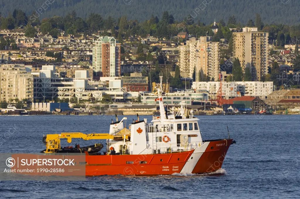 Coast Guard vessel motoring in front of Lonsdale and the North Shore, Vancouver, British Columbia, Canada