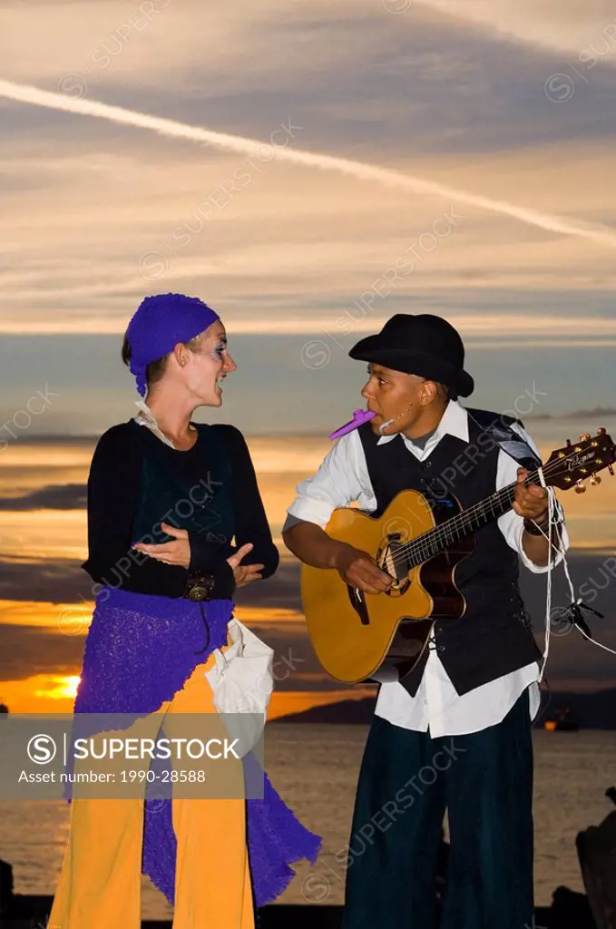 Street performers at dusk with English Bay behind, British Columbia, Canada